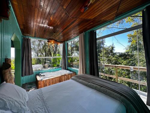 a bedroom with a bed and a window and a tub at Pousada Vale de Luz FW in Frederico Westphalen