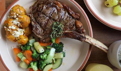 a plate of food with a steak and vegetables at Glamping Al Pie del Cerro in San Fernando