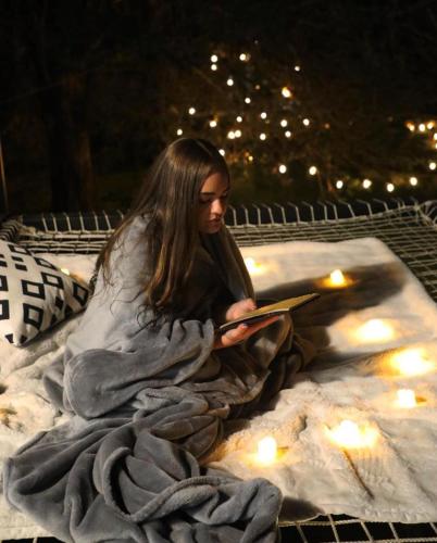 a woman sitting on a blanket reading a book at Glamping Al Pie del Cerro in San Fernando