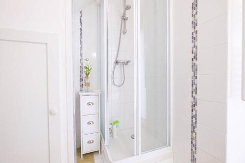 une salle de bain blanche avec une douche et un lavabo dans l'établissement Les toits de Fontainebleau, à Fontainebleau