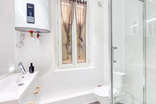 une salle de bain blanche avec douche et toilettes dans l'établissement Zen résidence, à Aubervilliers