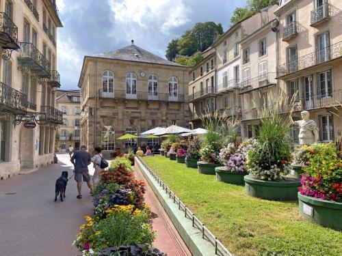 un homme qui promet un chien dans une cour fleurie dans l'établissement La Castalie, à Plombières-les-Bains