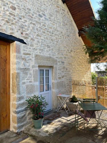 a stone house with a white door and a table at La Parenthèse, Les Gîtes de Montfaucon in Montfaucon