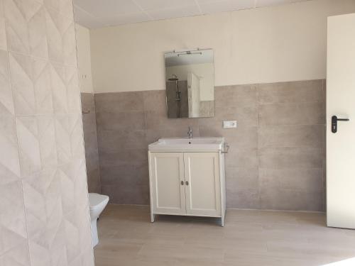 ein Badezimmer mit Waschbecken, Toilette und Spiegel in der Unterkunft El Algar Casa Rural in La Carlota