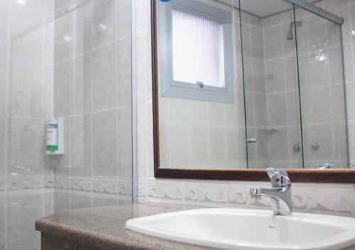 a bathroom with a sink and a mirror at Master Grande Hotel - Próximo ao Palácio do Governo in Porto Alegre