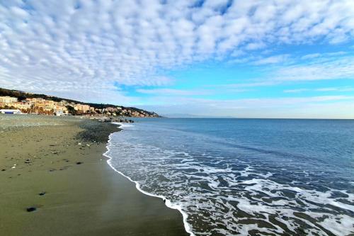 a beach with a cloudy sky and the ocean at Via Vernazza 30 mt dal mare in Cogoleto