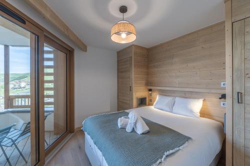 a bedroom with a bed and a large window and a tub at Alpe d'Huez Houses - L'Emparis - PHOENIX3 - Pour 5 SKI IN SKI OUT Wellness et vue magnifique in L'Alpe-d'Huez