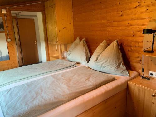 a bed in a room with a wooden wall at Auszeit 2 0 Digital Detox in Obergrünburg