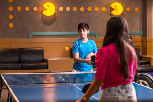 a young man and a woman playing ping pong at Blue Tree Thermas de Lins Resort in Lins
