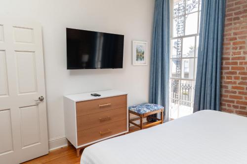 a bedroom with a bed and a dresser with a tv at Inn on St. Peter, a French Quarter Guest Houses Property in New Orleans