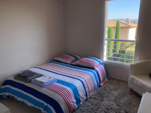 un lit avec une couverture rayée dans une pièce avec une fenêtre dans l'établissement Beautiful AC house with swimming pool Aix center, à Aix-en-Provence