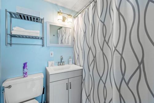 Un baño con lavabo y cortina de ducha. en Cozy 1-Bedroom Suite Steps from the Beach (464), en Old Orchard Beach