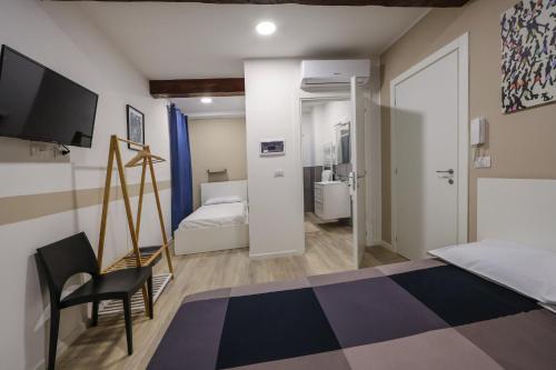 a bedroom with a bed and a chair and a television at Residence della Accademia in Modena