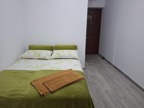 a bed with a green blanket and two pillows at Anna Home in Râmnicu Vâlcea
