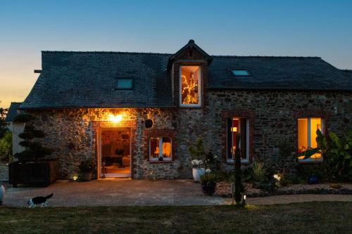 a stone house with a cat standing outside of it at Chambres d'hôtes avec Jacuzzi in Pouancé