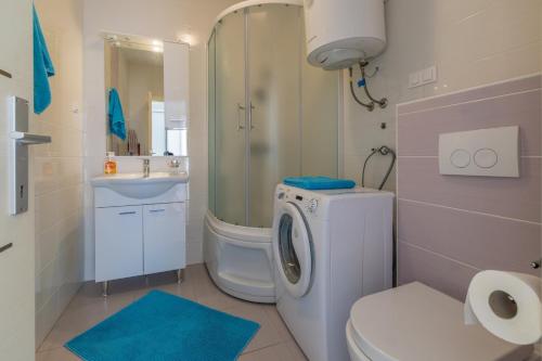a bathroom with a toilet a sink and a washing machine at Melanie in Crikvenica