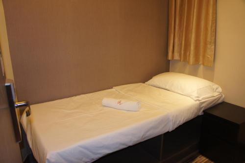 a small bed with a white towel on it at Homy Inn North Point in Hong Kong