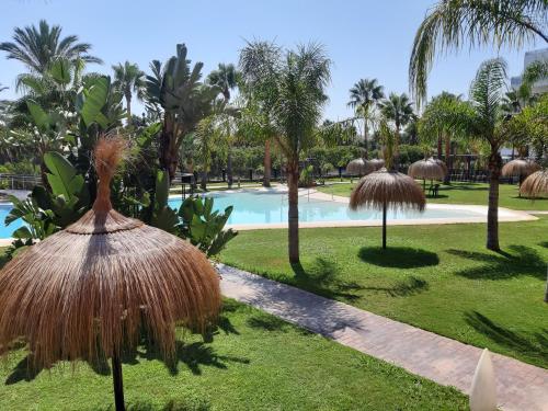 a resort with a swimming pool and palm trees at Costa Tropical Comfortable Apartment Playa Granada in Motril