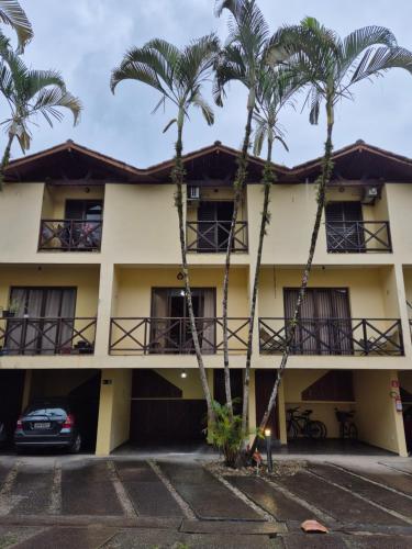 a building with palm trees in front of it at Casa 7 em Ubatuba no Centro Condomínio com Piscina e Churrasqueira in Ubatuba