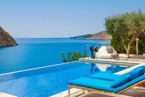 a pool with two blue lounge chairs next to the water at Braunis Horio Villas in Asos