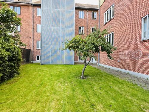a small tree in a yard in front of a building at aday - Sunny Studio Apartment in Aalborg