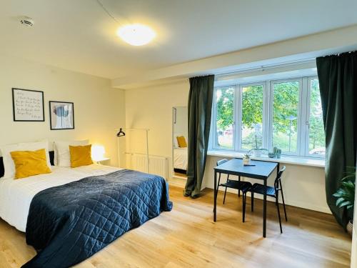 Un dormitorio con una cama y una mesa y ventanas. en aday - Holiday charming Studio, en Aalborg
