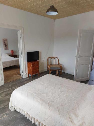 une chambre avec un lit blanc et une télévision dans l'établissement atelier du pain, à Mesvres