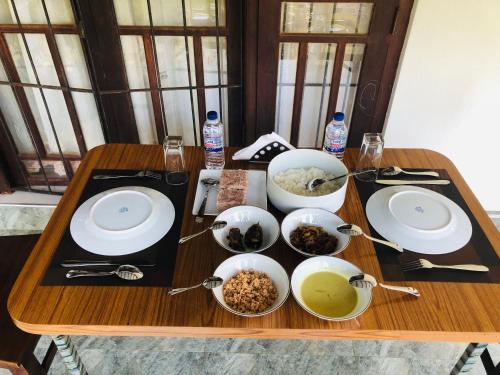 a wooden table topped with plates and bowls of food at Kottamba Villa Tangalle in Tangalle