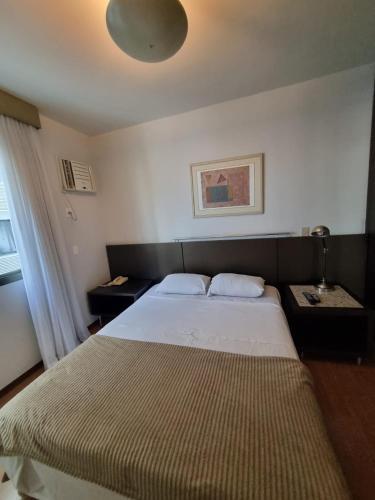 a bedroom with a large bed and a lamp at Sofisticação na Savassi in Belo Horizonte