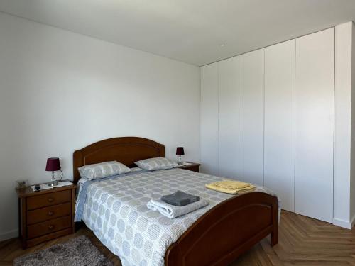 une chambre avec un lit avec une tête de lit en bois et des murs blancs dans l'établissement Maison bord mer près de le Lisbonne, à Charneca
