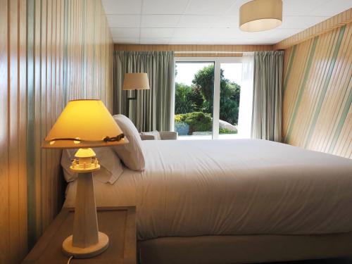 - une chambre avec un grand lit et une lampe jaune dans l'établissement La Maison du Château de Sable, à Porspoder