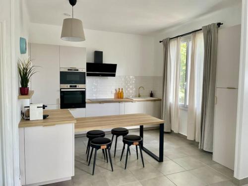 - une cuisine avec une table et des tabourets en bois dans l'établissement T3 avec jardin, proche plage & commodités, à Fos-sur-Mer