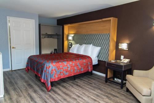 a hotel room with a bed and a chair at Columbus Inn and Suites in Columbus