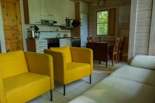 a kitchen with two yellow chairs and a table at Holiday Village Anttoora - Anttooran Lomakylä in Pori