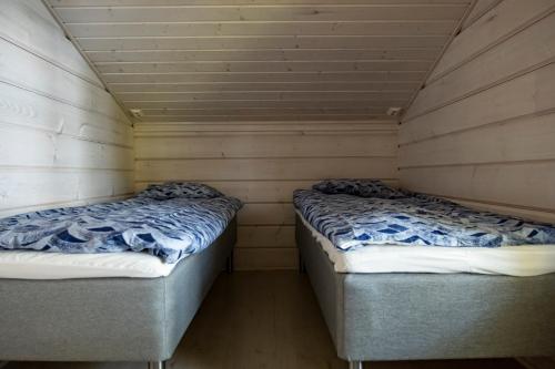 two beds in a room with wooden walls at Holiday Village Anttoora - Anttooran Lomakylä in Pori