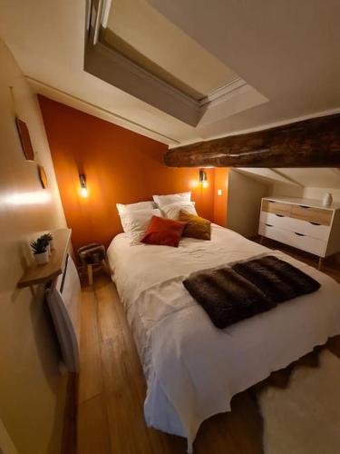 une chambre avec un grand lit blanc avec des murs orange dans l'établissement Magnifique cosy loft au cœur du centre ville, à Saint-Étienne
