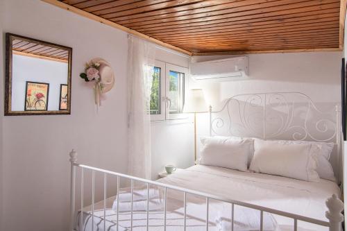 a bedroom with a white bed with a wooden ceiling at Nikos Sunset Penthouse in Mastambás