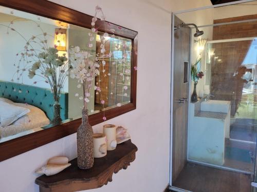 a bathroom with a mirror and a vase on a shelf at Villa Jardim Mar in Anchieta
