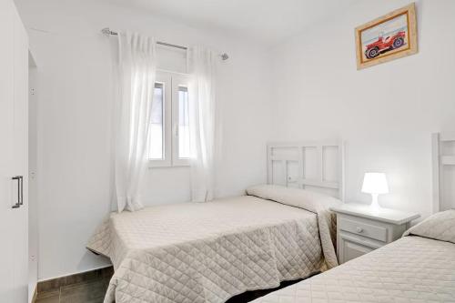 Un dormitorio blanco con dos camas y una ventana. en Casa Orquidea, en El Palmar