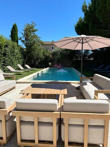 une piscine avec une table, des chaises et un parasol dans l'établissement Mas le petit Paradou, à Paradou