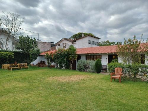 a house with a yard with a chair in it at Hostal Mochiliers Bed and Breakfast in Cuenca