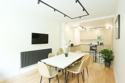 une salle à manger avec une table et des chaises blanches dans l'établissement Charmant appartement 8 personnes avec Sauna, à Paris