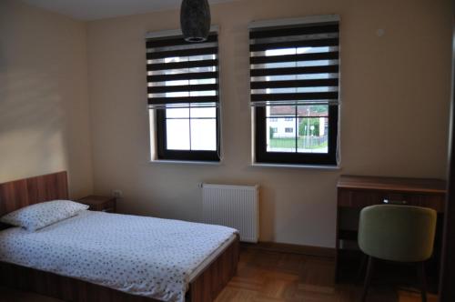 a bedroom with two windows and a bed and a chair at Apartments Divanhana 1 in Kiseljak