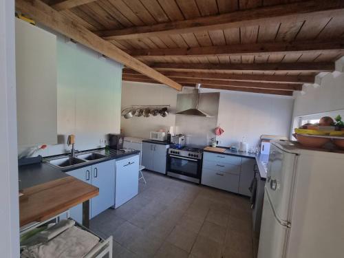 a large kitchen with white appliances and a wooden ceiling at Guest House Azeitão, Wine, Lodge in Villa Nogueira