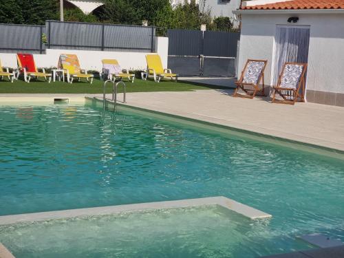 a swimming pool with chairs and a group at Guest House Azeitão, Wine, Lodge in Villa Nogueira