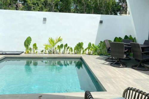 a swimming pool with chairs next to a white wall at Casa Kaan, Senderos, Mayakoba in Playa del Carmen