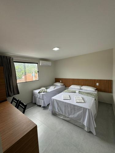 a bedroom with two beds and a window at pousada praia bela japaratinga in Japaratinga