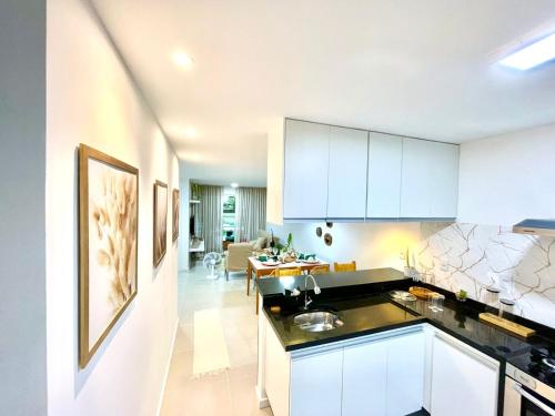 eine Küche mit weißen Schränken und ein Wohnzimmer in der Unterkunft Jacuipe Country in Campos