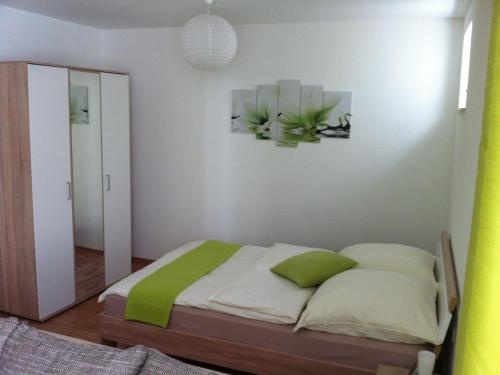 1 dormitorio con cama con almohadas verdes y espejo en Ferienwohnung Heike en Dettingen an der Erms