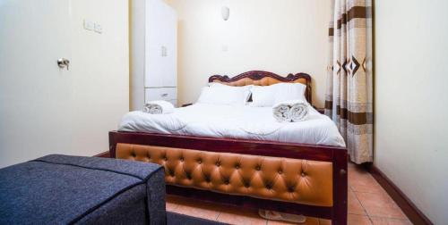 ナイロビにあるHoney Pie Executive Suite Apartmentの木製のヘッドボードが付いたベッドのある寝室